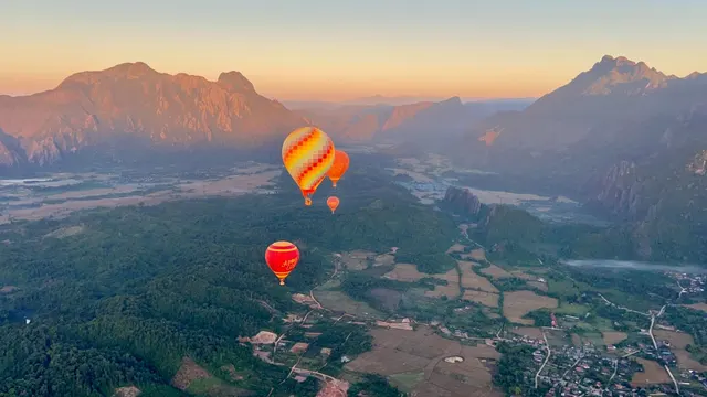 Hot-air balloons over a valley of limestone peaks at sunrise.